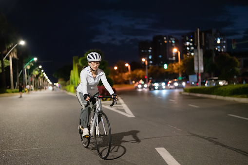 Asian woman riding a road bike at night