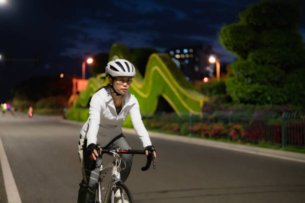 femme asiatique faisant du vélo de route la nuit - mental health women asian ethnicity bicycle photos et images de collection