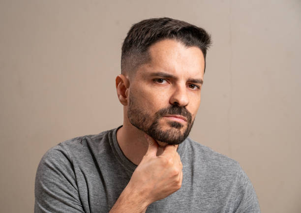istock Gray haired man looking at camera with hand on chin on pastel background. 1789463320
