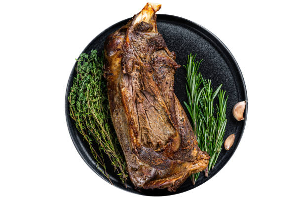 istock Roasted lamb mutton shoulder meat on a plate with knife and fork. Black background. Top view 1789495147