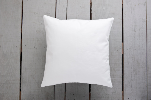 White cushion on grey wooden background.
