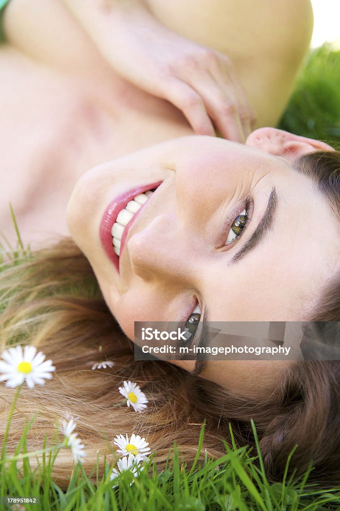 Caucasiana Jovem mulher sorridente ao ar livre com flores - Foto de stock de Deitar royalty-free