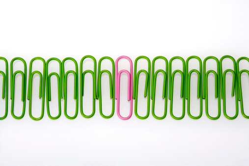 Paperclips lined up in a row with one odd one in the bunch.