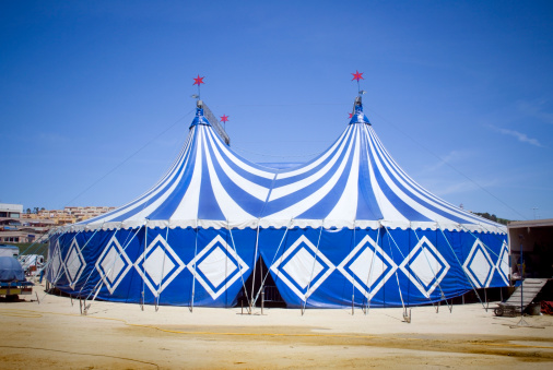 A blue and white circus tent with red stars on the top.