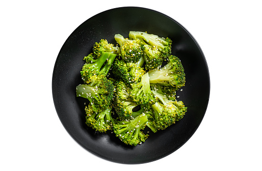 Boiled broccoli with spices in a plate.  Isolated, white background. Top view