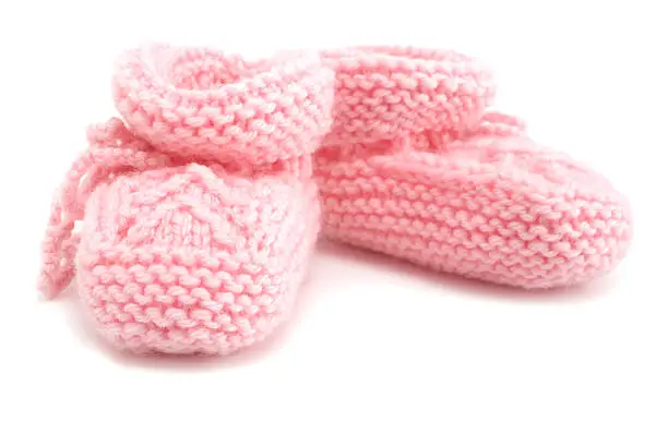 Pair of hand knitted pink baby booties on white background. 
