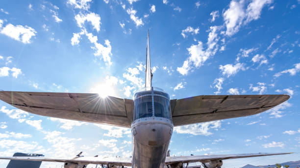 Rear window of military plane and tail with cloudy sky