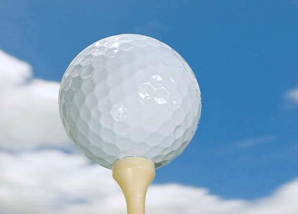 istock golf ball on tee against blue sky with puffy clouds 178957195