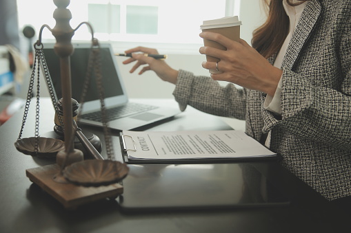 Business and lawyers discussing contract papers with brass scale on desk in office. Law, legal services, advice, justice and law concept picture with film grain effect