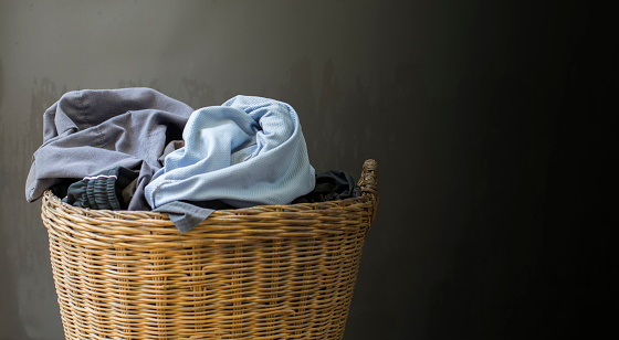 The clothes in the basket are prepared to wash and clean with a dark gray background with space.