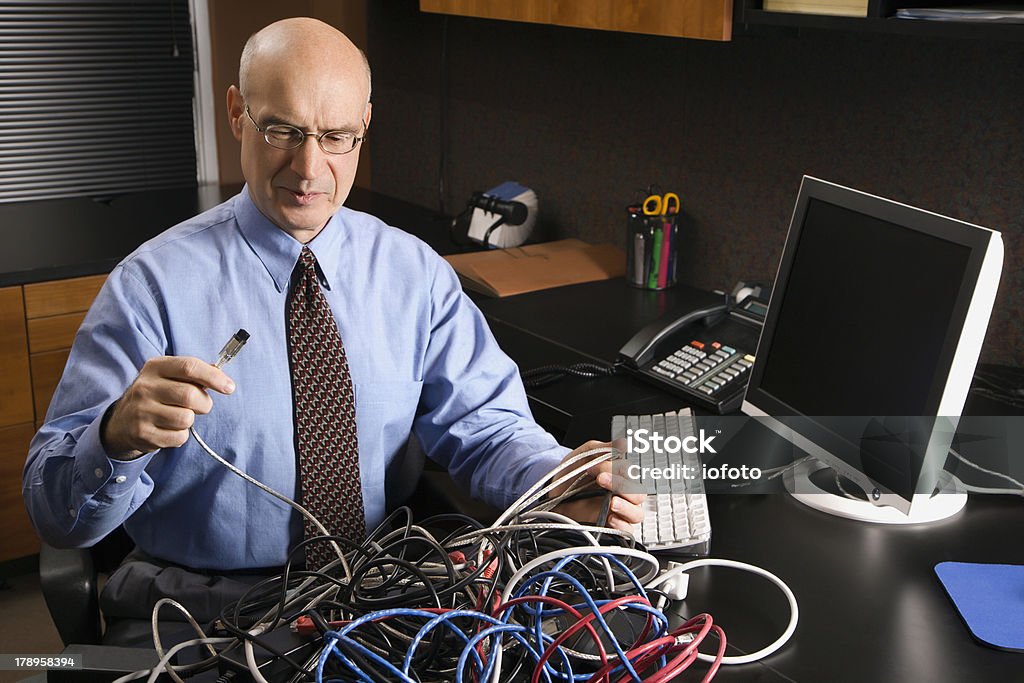 Caucásico ejecutivo en una maraña cubierta de cables para PC. - Foto de stock de Cable libre de derechos
