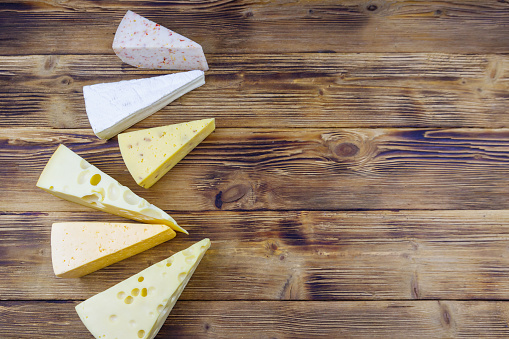 Set of various types of cheese on wooden table. Top view, copy space