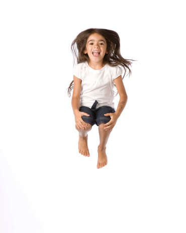 Five year old Hispanic girl jumps in the air. 