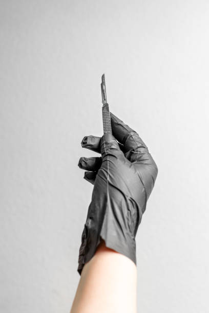 a scalpel in a hand that's wearing a black latex glove. - professional occupation human foot clothing concentration imagens e fotografias de stock