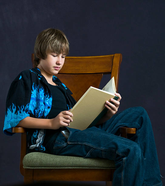 istock Teenage boy reading while seated 178964447