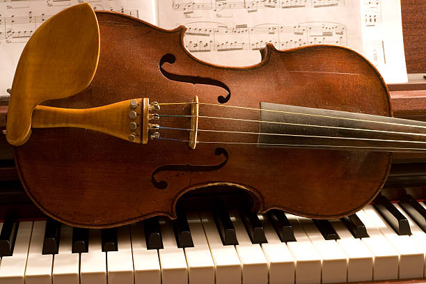 Velho violino em pó teclas de piano - foto de acervo