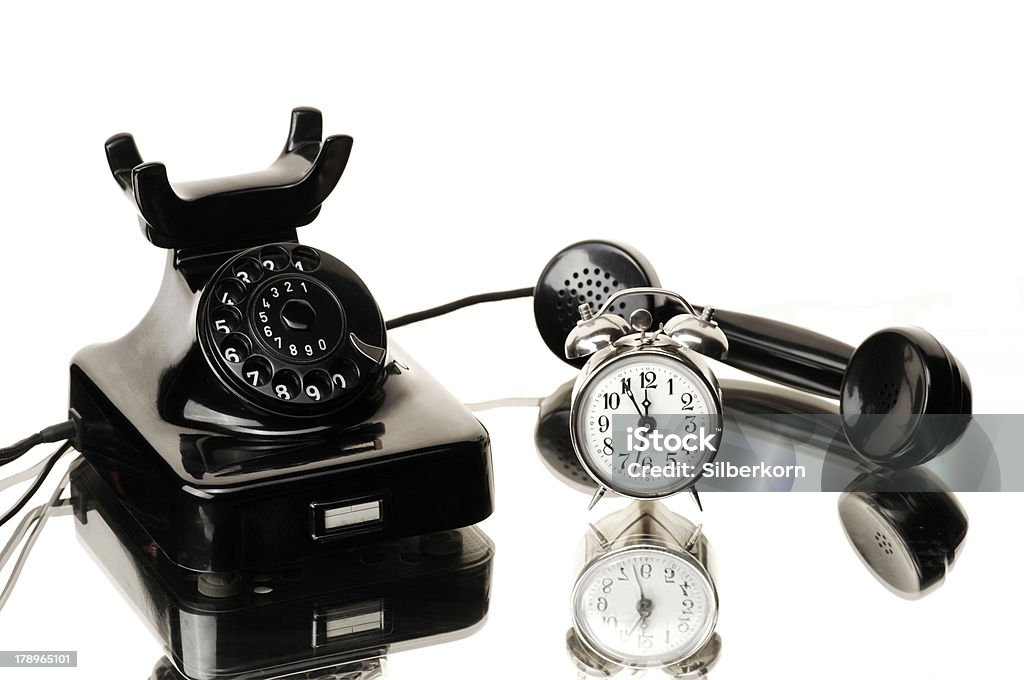 Telephone Black bakelite telephone and alarm clock 5 to 12 - time to make a call Candlestick Phone Stock Photo