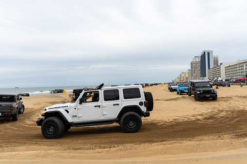 Virginia Beach, VA, USA - November 11, 2023
White jeep going around a sand course with long lines of jeeps in the background at the annual Jeep Fest held at Virginia Beach, VA. Gathering of Jeep owners from across the country come to meet fellow jeep owners and practice new driving skills.