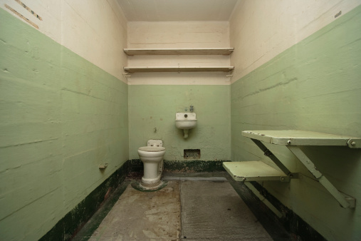 A wide-angle view of a gloomy, grimy prison cell.