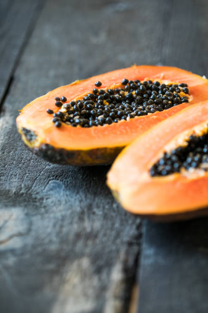istock Whole papaya fruit and half with seeds on wooden background 1789684544