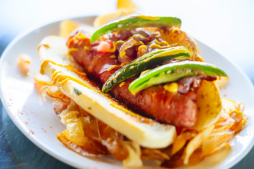 Delicious gourmet hot dog with fries and avocado