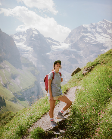 Portrait of cheerful woman on hiking trail in Switzerland. She is smiling to the camera. Shot on camera film