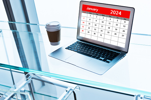 Calendar of January 2024 on laptop screen with cup of coffee beside