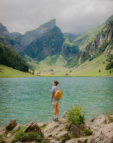 Cheerful woman standing on the background of  Seealpsee lake in Appenzell. Shot on camera film