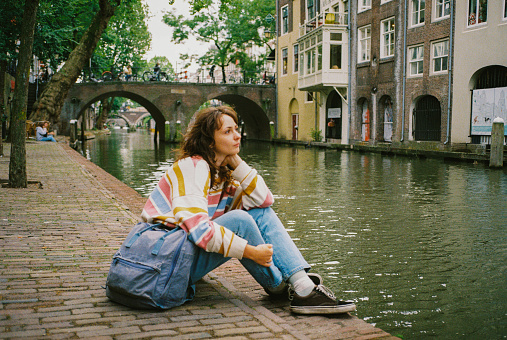 Woman sitting near canal in Utrecht and enjoying peace and quite of dutch town
