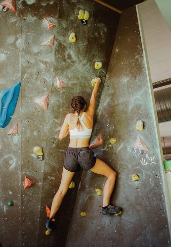 Determined woman climbing in bouldering gym
