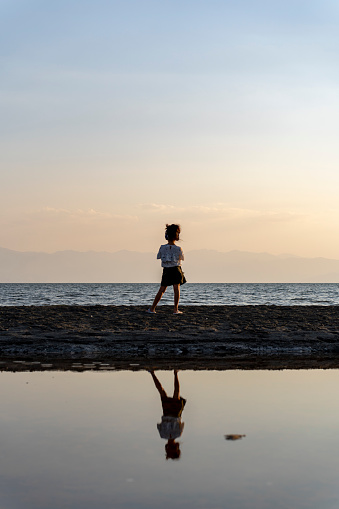 Girl walking at sunset. Walking by the sea. Walking on the beach. Motivation. Loneliness.