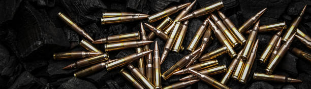 Cartridges for automatic carbine caliber .223 on charcoal. Ammunition for automatic and semi-automatic rifles. Dark background.
