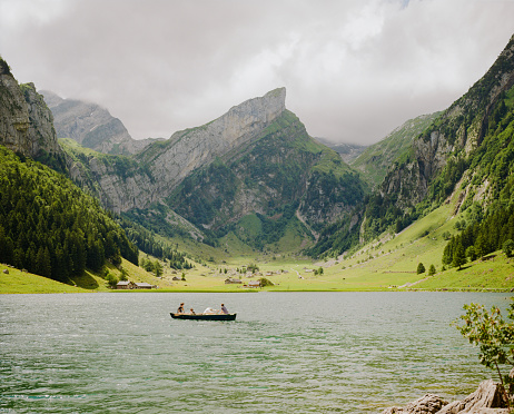 Family on boat on Seealpsee lake in Swiss Alps  in summer. Shot on camera film