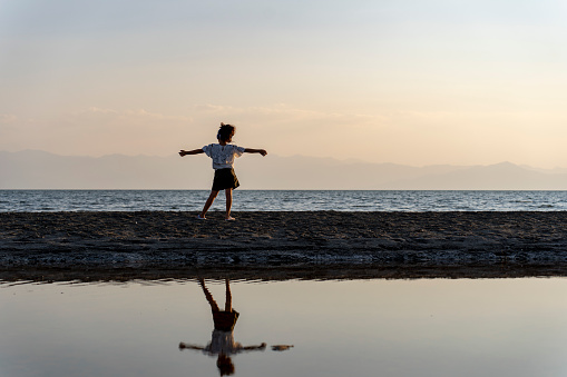 Girl walking at sunset. Walking by the sea. Walking on the beach. Motivation. Loneliness.