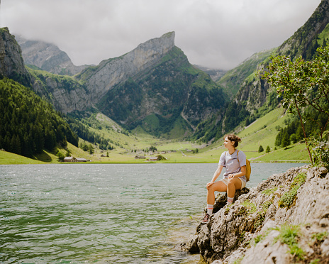 Woman sitting  near Seealpsee lake and enjoys serenity after the hike Shot on camera film