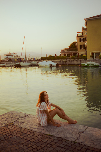 Cheerful woman enjoys serenity  near lake Garda during summer vacation. Shot on camera film