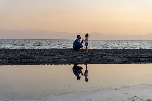 Father and daughter hiking at sunset. Walking on the beach. Pleasant moments by the sea. Father and daughter love. Father's day concept.