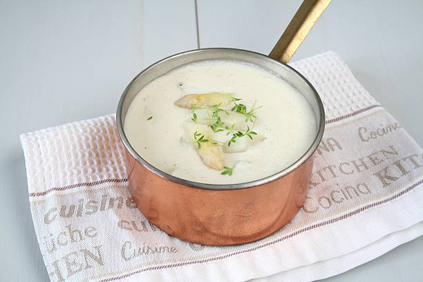 Overhead view of a dish of white asparagus served with prawns and a hollandaise sauce.