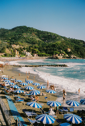 Scenic view of Vernazza beach with blue umbrellas  and chaise lounges at sunset. Shot on camera film