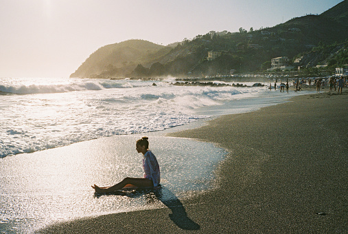 Carefree cheerful teenage girl  walking on the beach. Shot on camera film