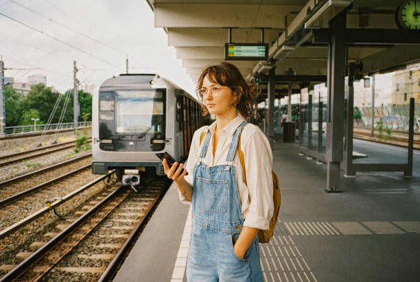 istock Woman using smartphone while waiting for the  train on station 1789738199