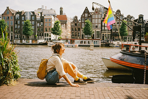 Portrait of  woman sitting on the background of LGBTQ+ flag on the boat in Amsterdam. Shot on camera film