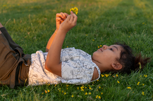 A girl lying on the lawn. Portrait of a girl in green nature. Portrait of a girl child. A girl child in nature.