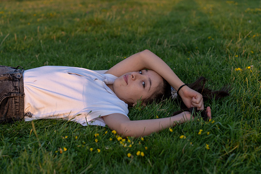 A girl lying on the lawn. Portrait of a girl in green nature. Portrait of a girl child. A girl child in nature.