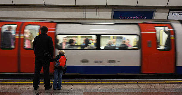 There goes the train Man and boy watch as the train passes by. london england rush hour underground train stock pictures, royalty-free photos & images