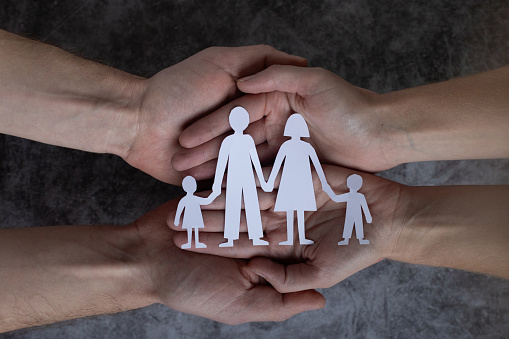 family and relationships, couple hands holding paper family with two children, care and protection concept