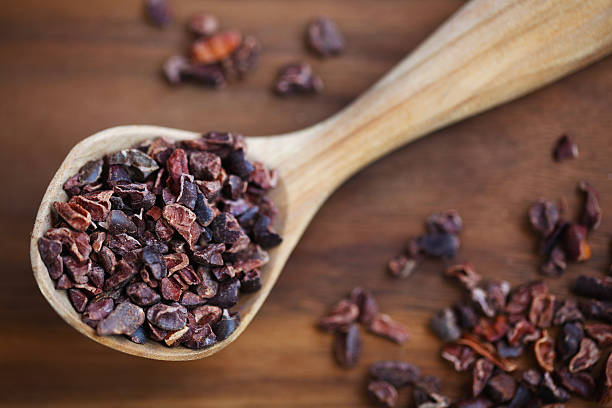 granos de cacao pura en una cuchara de madera - plumín fotografías e imágenes de stock