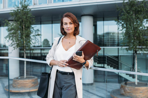 istock Confident middle-aged female holding a folder standing against business building 1789800968