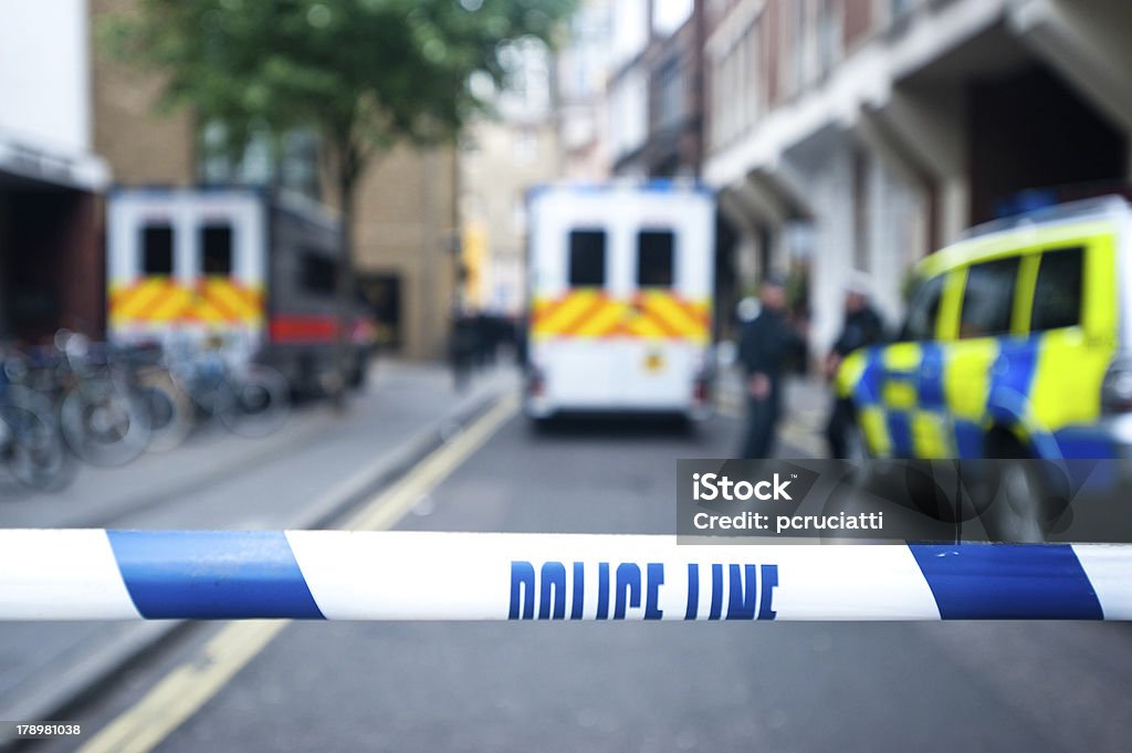 Safety police line tape on crime scene Police officers and vans behind safety police line tape. Police Force Stock Photo