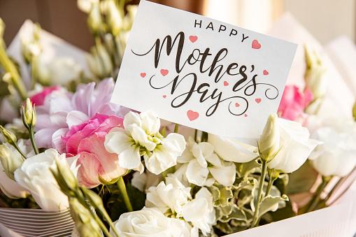 hand with Mothers day greeting card.Happy Mothers Day concept. beautiful bouquet of colorful spring flowers. roses, ranunculus,daisy, gerber.